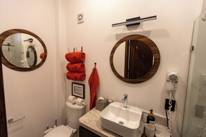 A bathroom with a white sink, a mirror, a towel rack with towels, a toilet, and a hand dryer. - La Mexicana, Puerto Vallarta  —Romantic Zone, within walking distance of Los Muertos Beach (Puerto Vallarta)