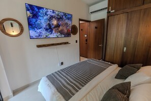A bedroom with a bed, a mounted TV, a wooden wardrobe, and a door. - La Mexicana, Puerto Vallarta—Romantic Zone, within walking distance of Los Muertos Beach (Puerto Vallarta)