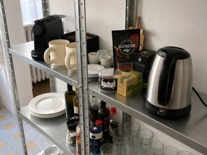 A kitchen area with a coffee maker, mugs, tea, and condiments on shelves. - Grand T2 lumineux • Gare St-Charles & Vieux-Port (Marseille)