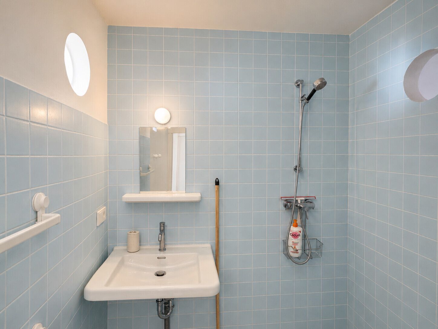 A bathroom with a sink, mirror, and shower.