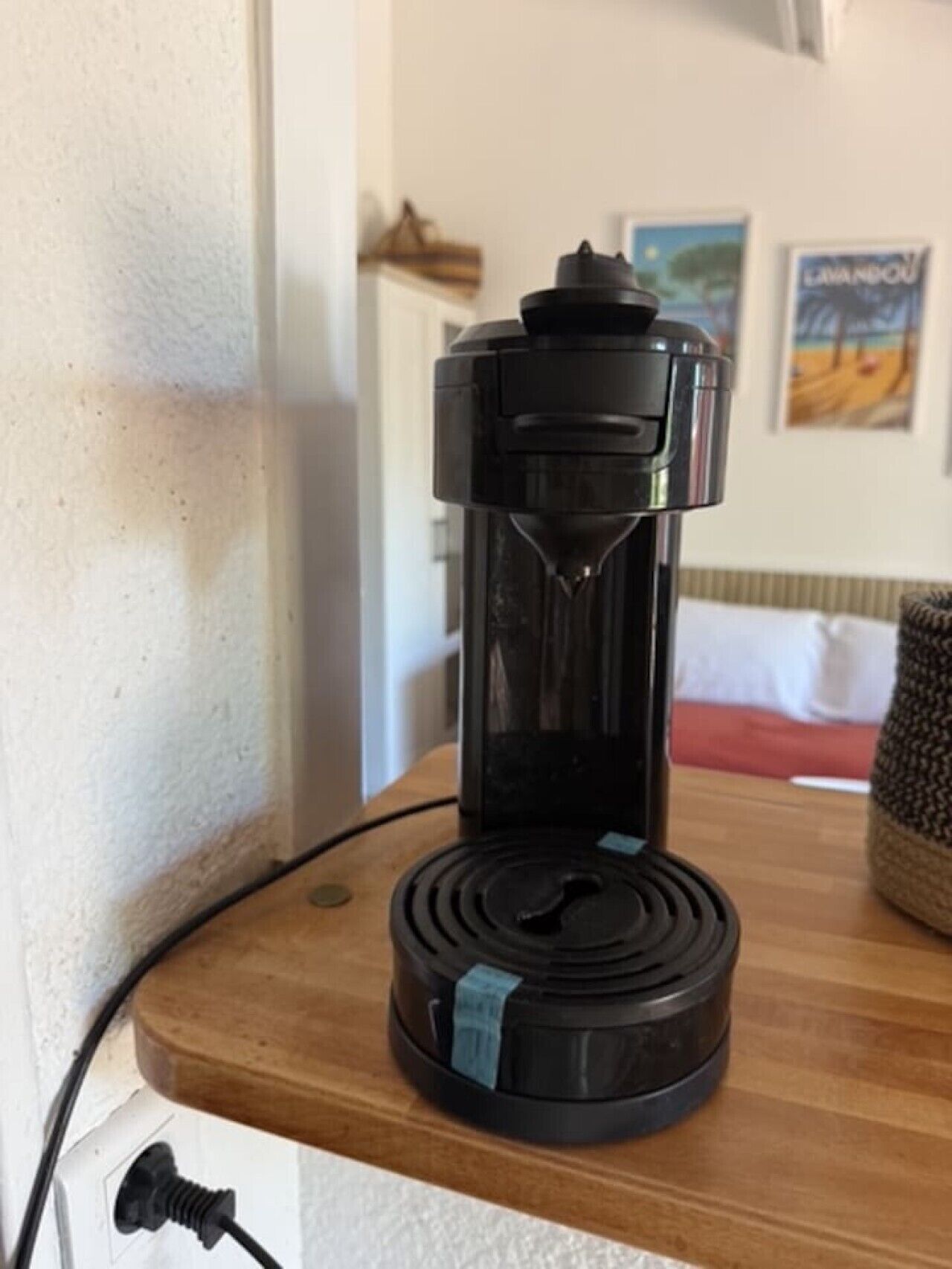 Een koffiezetapparaat op een houten oppervlak met een stroomkabel aangesloten.