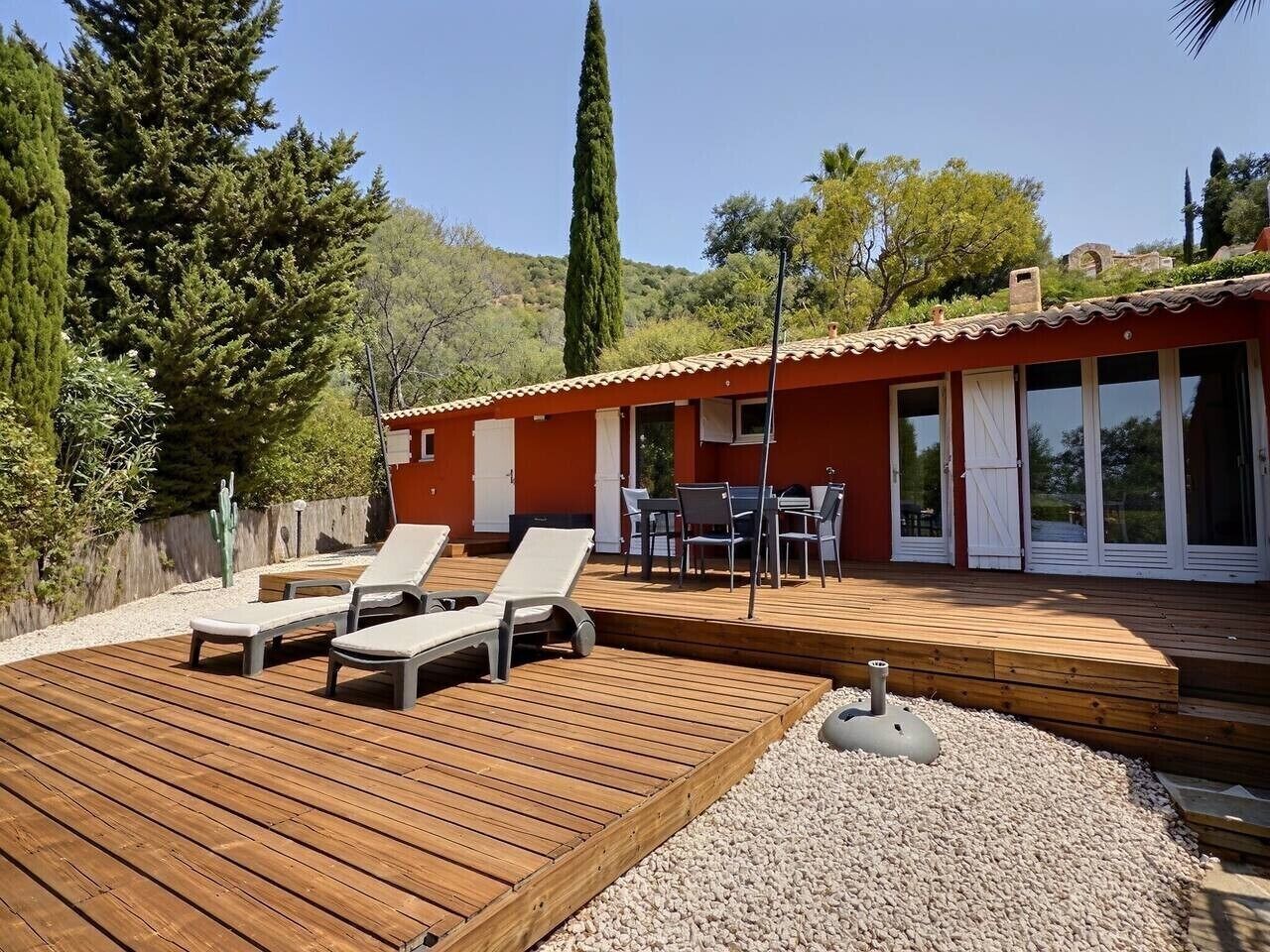 A wooden deck with lounge chairs, a patio table, and a barbecue grill.