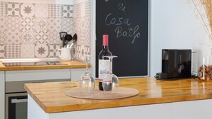 En køkkenbordplade med en vinflaske, et glas og en kaffemaskine.