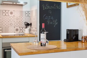 Uma bancada de cozinha com uma garrafa de vinho, um copo e uma cafeteira.
