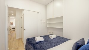 A bedroom with a bed, a wardrobe, and a door leading to another room. - Bairro Alto Stylish II by Homing (Lisbon)