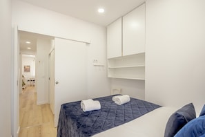 A bedroom with a bed, a wardrobe, and a door leading to another room. - Bairro Alto Stylish II by Homing (Lisbon)