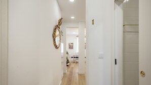 A hallway with a wooden floor, white walls, and a door with a gold handle. - Bairro Alto Stylish II by Homing (Lisbon)