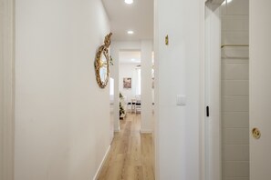 A hallway with a wooden floor, white walls, and a door with a gold handle. - Bairro Alto Stylish II by Homing (Lisbon)