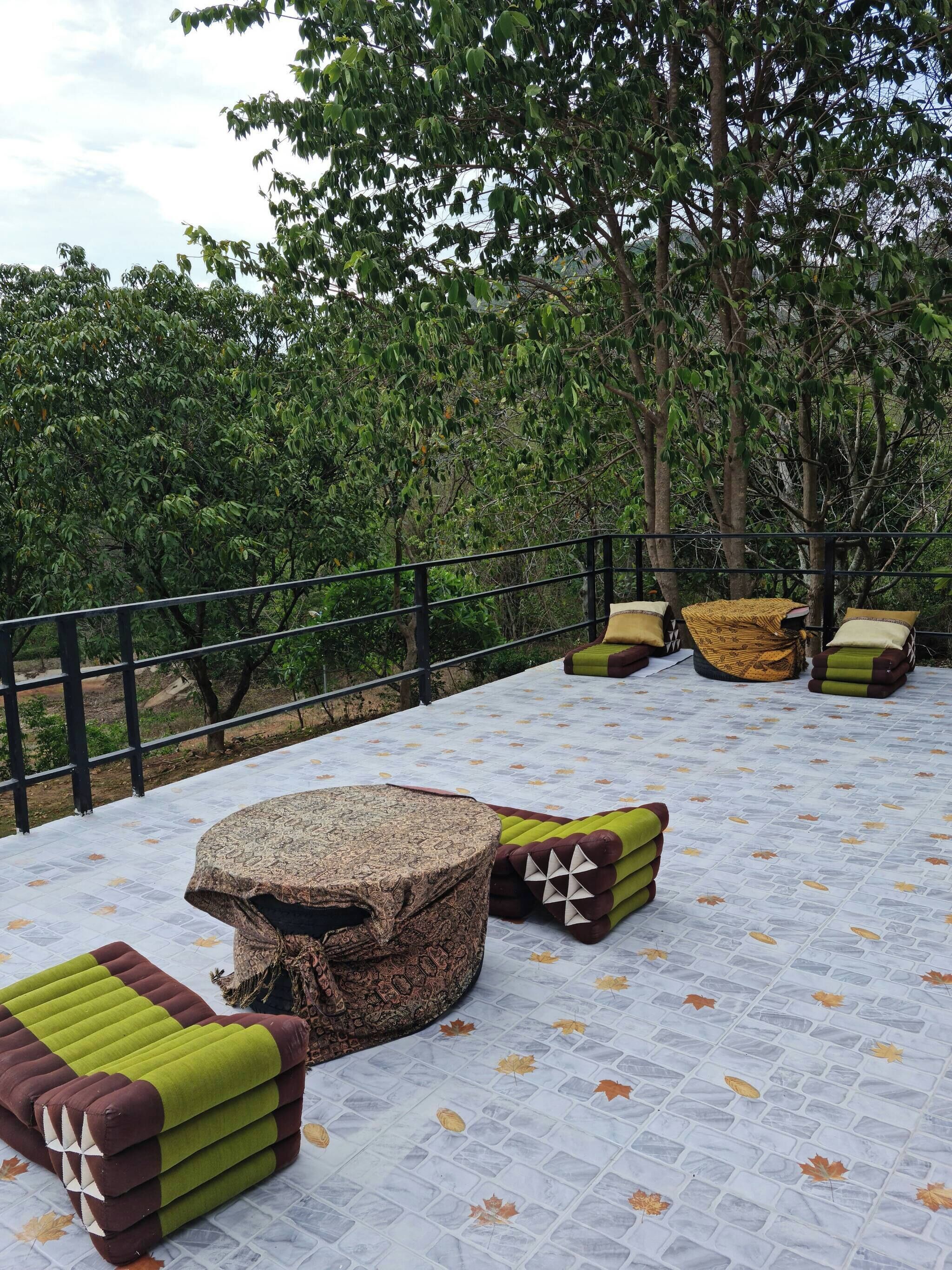 Un área de estar al aire libre con suelo estampado, asientos acolchados y una mesa de piedra.