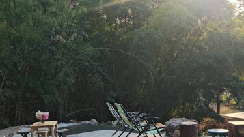 An outdoor seating area with tables and chairs, surrounded by dense foliage.