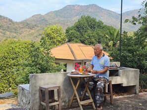 A man sitting at a table with a view of a mountainous landscape. - Mountain Front Family Home Big Balcony For 4 Rare Birds, Bikes (Kaeng Krachan)