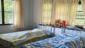 A room with two single beds, a window with curtains, an air conditioning unit, and a small table with items on it. - Mountain Front Family Home Big Balcony For 4 Rare Birds, Bikes (Kaeng Krachan)
