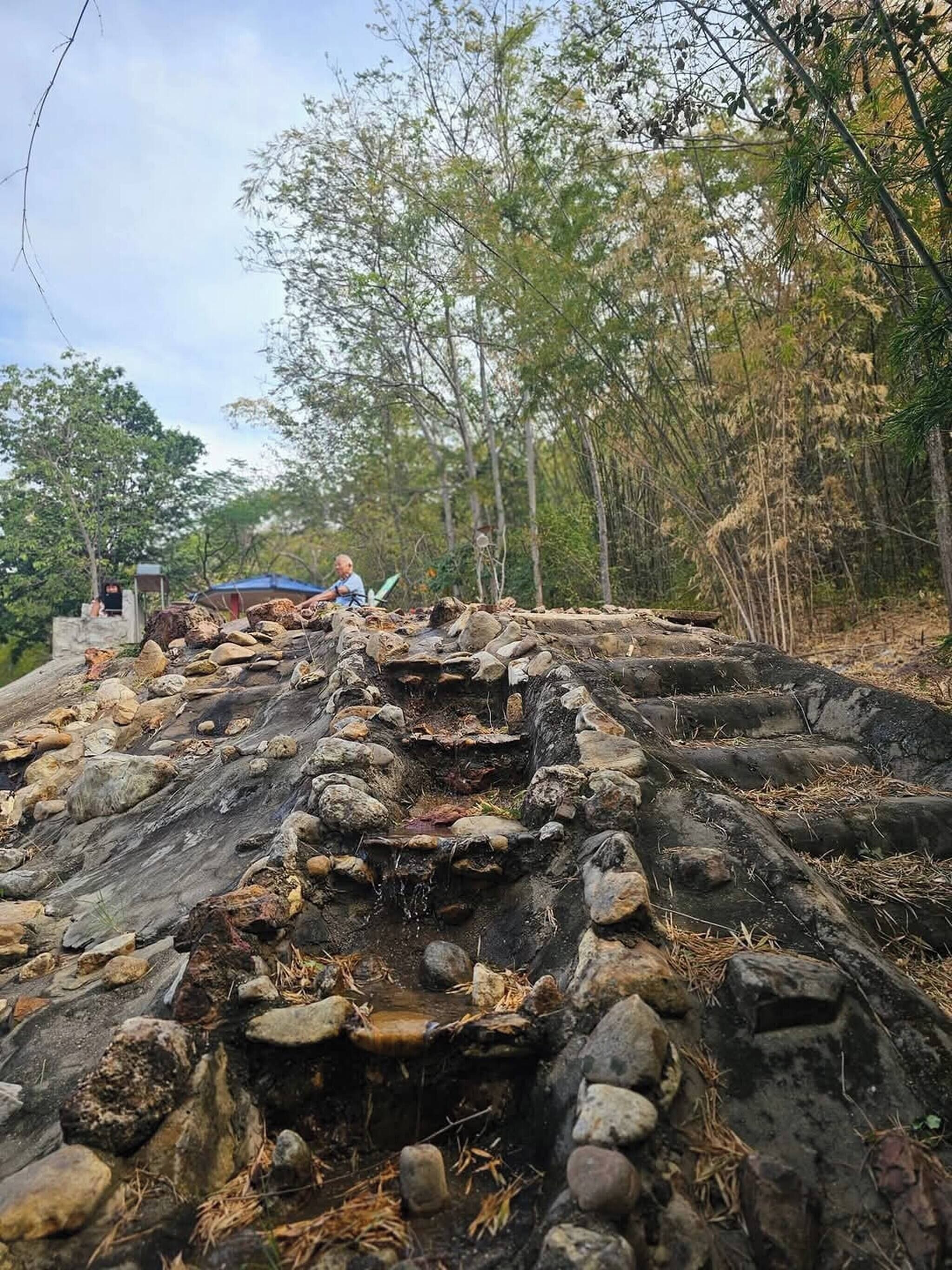 A rocky outdoor area with a person sitting on a bench.
