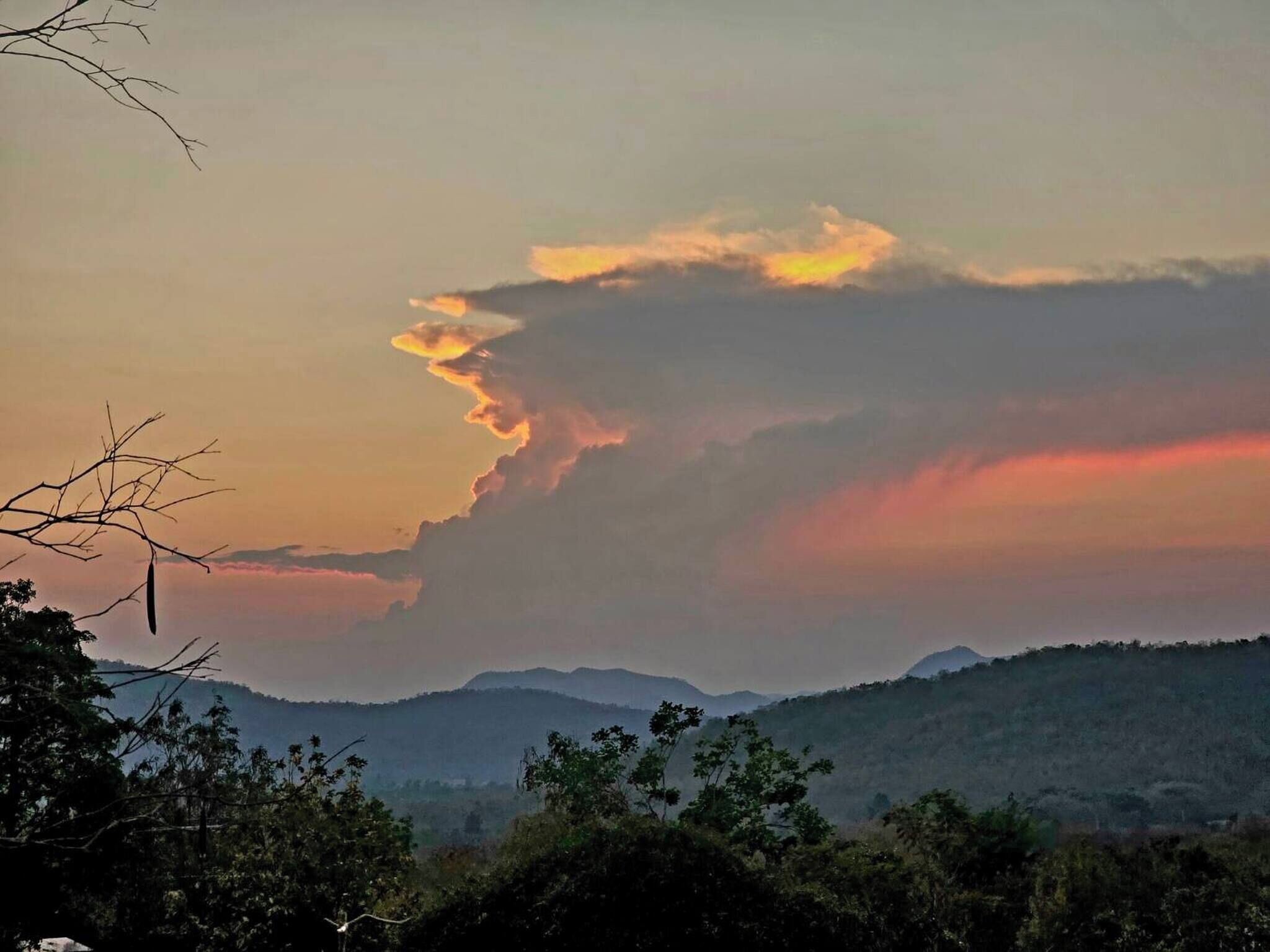 A landscape with a mountain range and a cloudy sky.