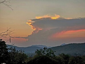 A landscape with a mountain range and a cloudy sky.