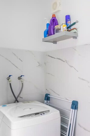 Une salle de bain équipée d’un chauffe-eau, d’un porte-serviettes et d’une étagère contenant des articles de toilette.