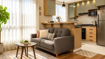 A modern living room with a grey sofa, a small round table, and a potted plant.
