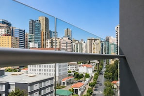 Un paisaje urbano con edificios modernos, cielo despejado y una calle con automóviles.