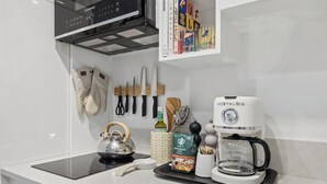 A kitchen with a coffee maker, a kettle, and a coffee pot on the counter. - The Big Yellow House Lofts by the beach (Summerland)