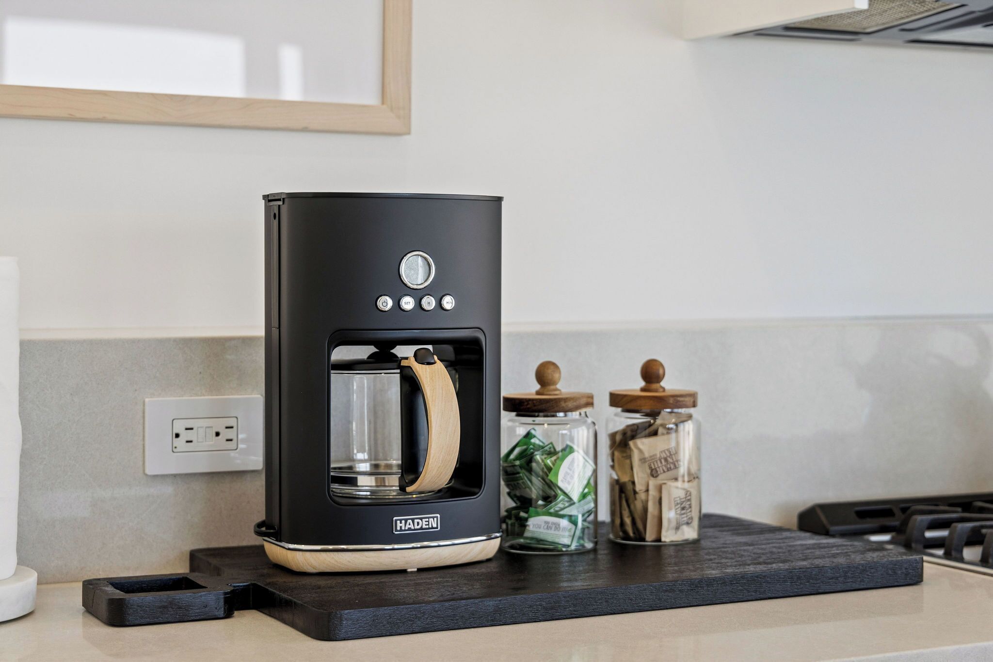 A black coffee maker with a wooden handle on a kitchen counter.