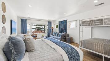 A modern bedroom with a bunk bed, a sofa, and a dining area with a view.