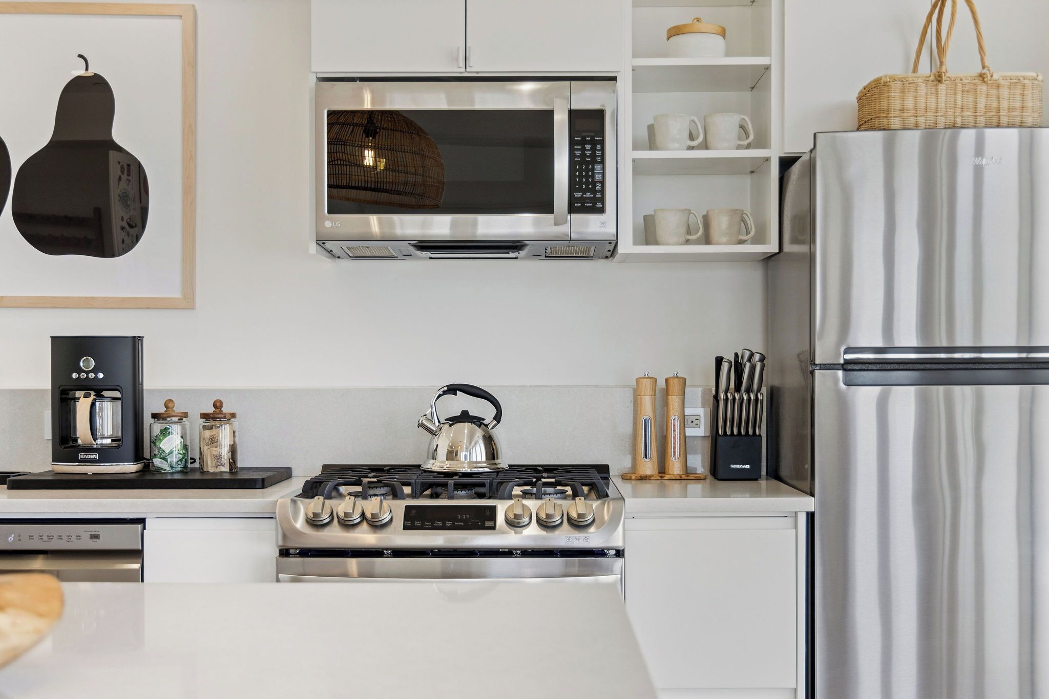 Une cuisine moderne équipée d’une cuisinière, d’un four à micro-ondes et d’un réfrigérateur en acier inoxydable.