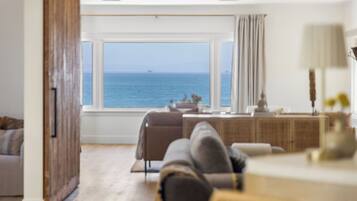 Ein modernes Wohnzimmer mit einem großen Fenster und Blick auf das Meer.