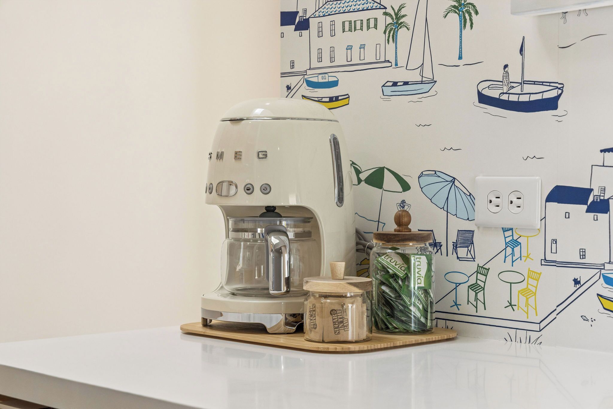Eine Küche mit Kaffeemaschine, Zuckerdose und einer Wand im Seestil.