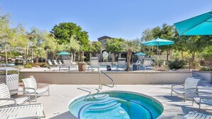 A pool area with lounge chairs and umbrellas, surrounded by trees and a building. - Scottsdale Stay  Near Spring Training Games (Scottsdale)