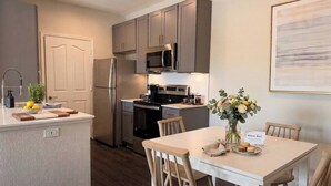 A modern kitchen with grey cabinets, stainless steel appliances, and a dining area with a table and chairs. - Scottsdale Stay  Near Spring Training Games (Scottsdale)
