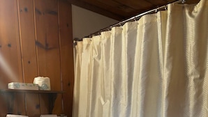 Un baño con inodoro, cortina de ducha y un estante con toallas.