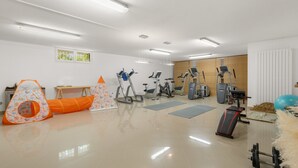 Uma academia com diversos equipamentos de exercício, incluindo esteiras, bicicletas ergométricas e um remo.