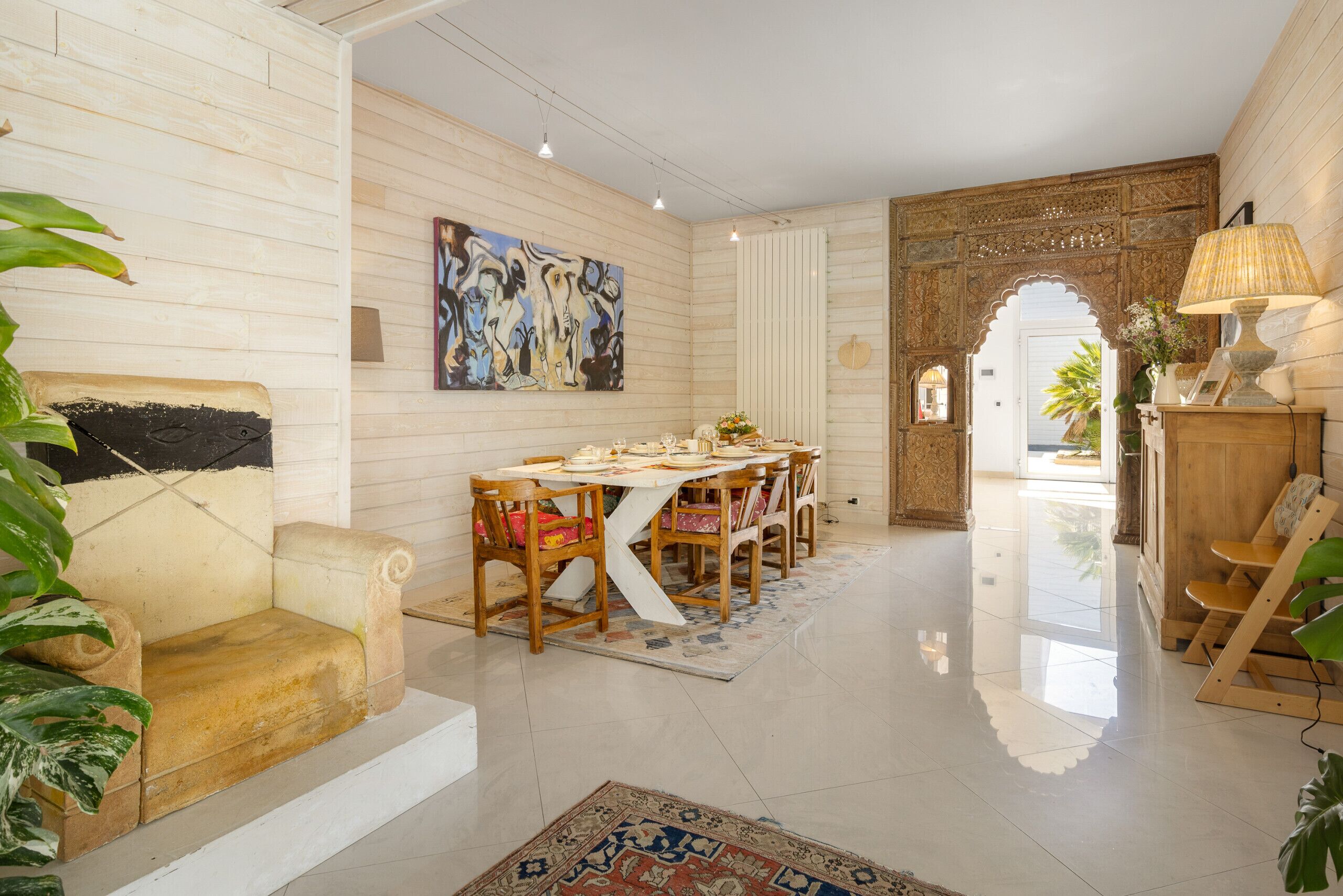 A dining area with a wooden table, chairs, and a painting on the wall.
