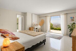 Ein Schlafzimmer mit Bett, Nachttisch und Blick ins Freie.