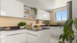 Uma cozinha moderna com armários brancos, uma ilha central e uma janela que oferece iluminação natural.
