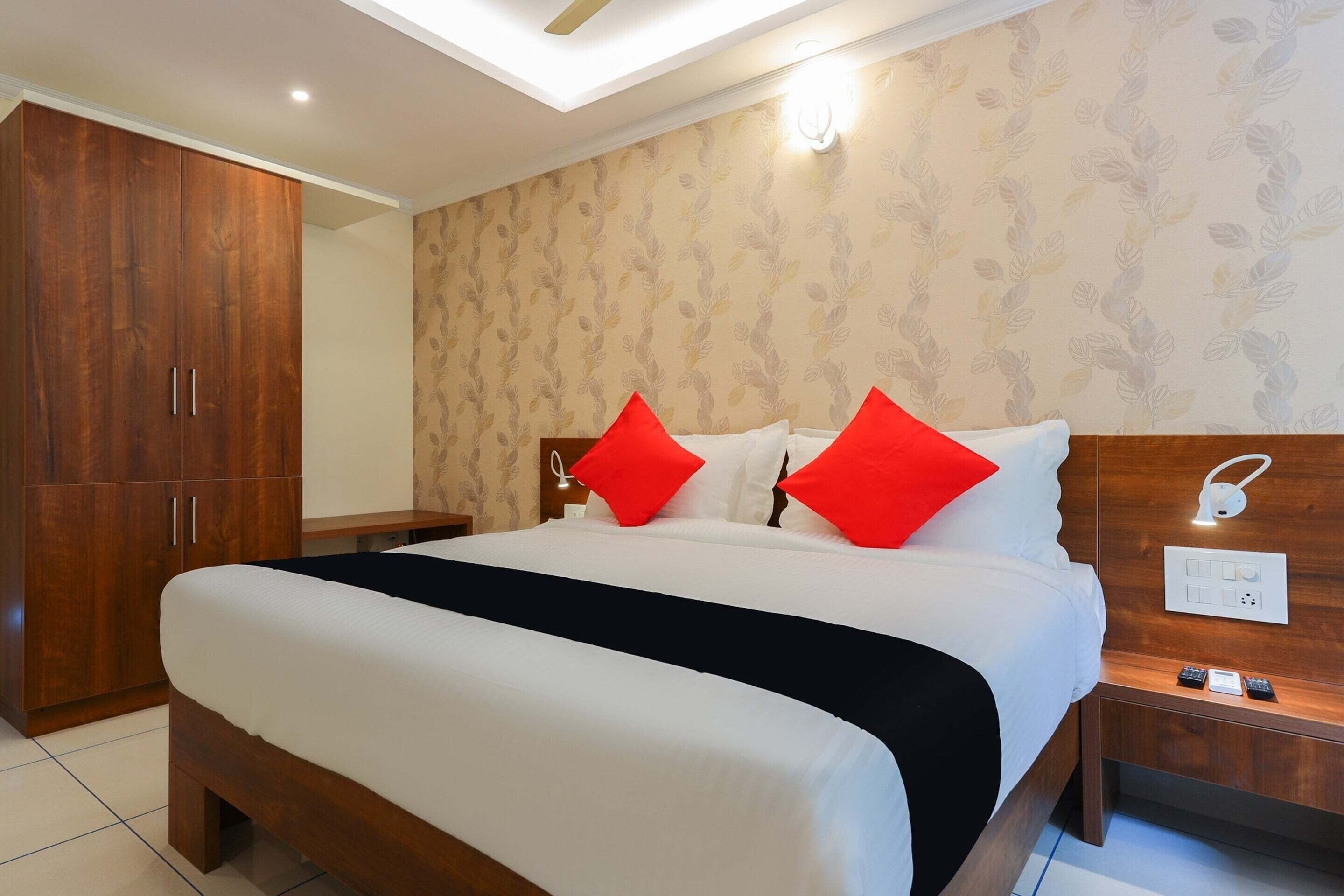 Habitación de hotel con una cama grande, armario de madera y mesita de noche con lámpara.