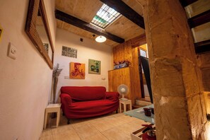 A cozy room with a red sofa, wooden beams, a skylight, and artwork on the walls. - 3 Cities Maison: Terraced House of Character close to Valletta (Bormla)