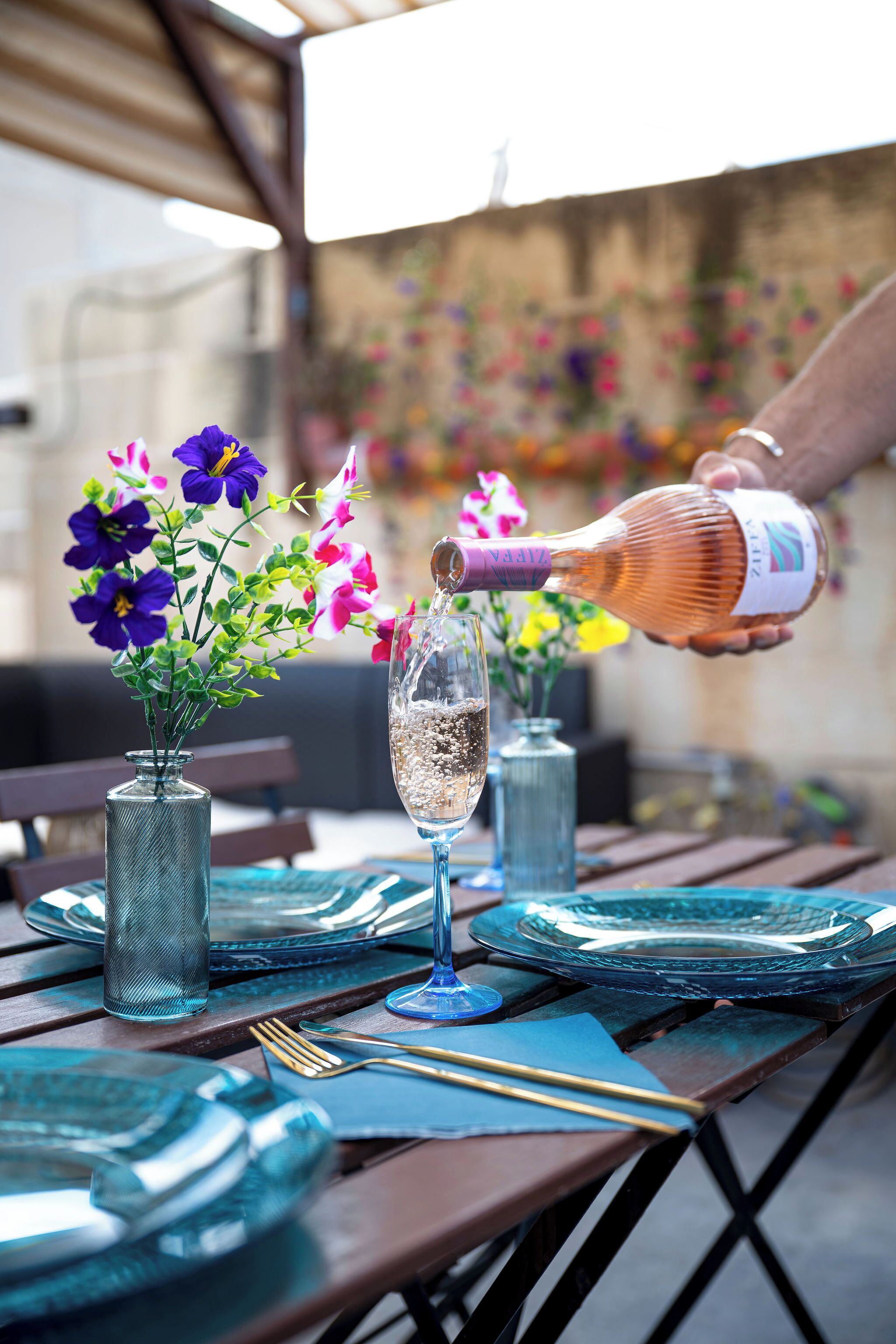 Una mesa dispuesta con una copa de champán, un florero con flores y una botella de champán.