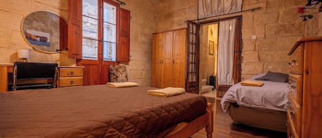 A cozy bedroom with a large bed, wooden wardrobe, and a bathroom with a bathtub.