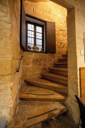 Una scala in pietra con gradini in legno che conduce a una finestra con persiana in legno.