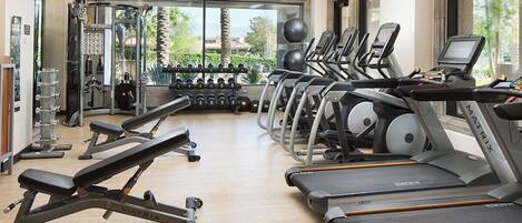 A gym with treadmills, weight machines, and dumbbells.