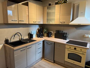 A modern kitchen with a dishwasher, double sink, and built-in oven.