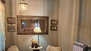 A cozy room with a wooden ceiling, a mirror, two chairs, a table with a lamp, and a radiator. - Refúgio das araucarias (Canela)