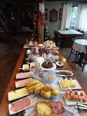 Una mesa de buffet con diversos alimentos y un árbol de Navidad al fondo.