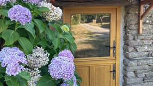 Un edificio in pietra con una porta in legno e un vialetto sterrato che vi conduce.