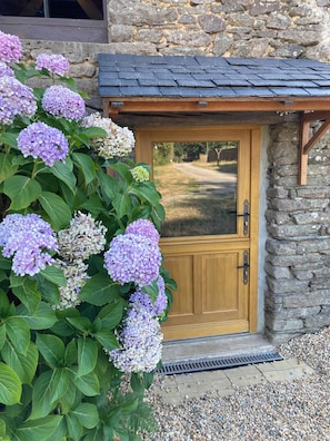 A stone building with a wooden door and a gravel pathway leading to it.