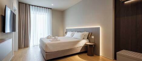 Une chambre moderne avec un grand lit, une table de chevet, un téléviseur à écran plat et une armoire intégrée.
