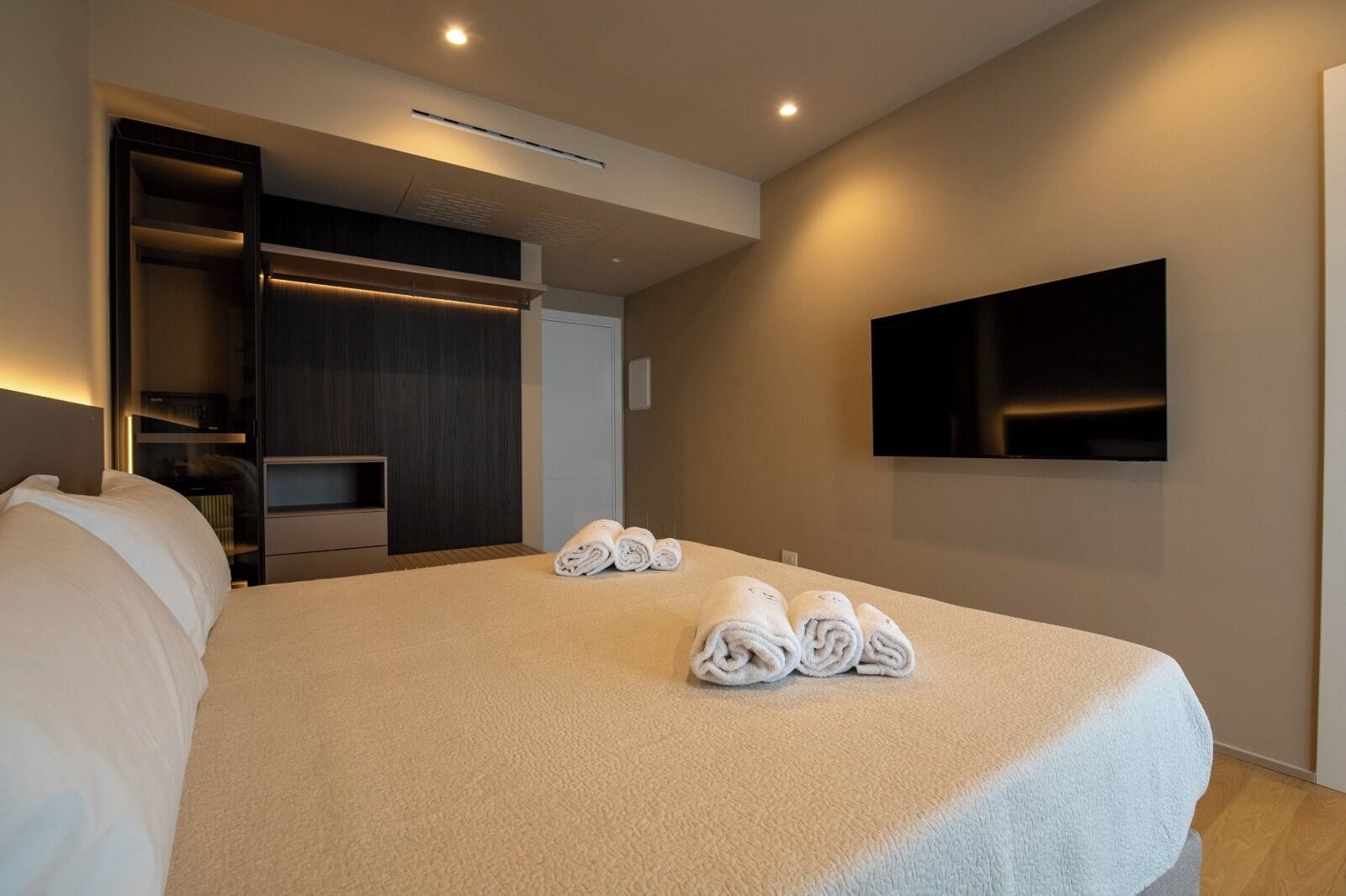 Une chambre d’hôtel moderne dotée d’un grand lit, d’un téléviseur à écran plat fixé au mur et d’un dressing.