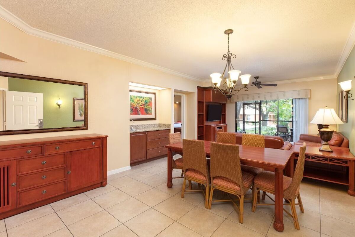 A dining area with a wooden table and chairs, a chandelier, and a view of the outdoors.