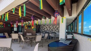 A dining area with tables and chairs, a bar area, and a view of the city. - Studio in Condo. w/ Pool and City View Bcm0403 (Recife)